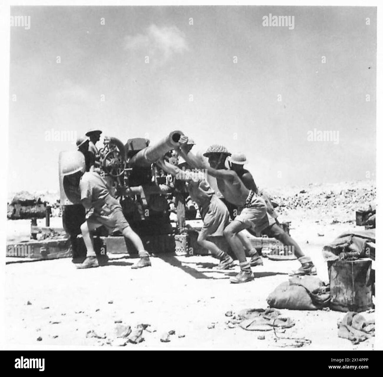 I membri dell'equipaggio utilizzano un cannone antiaereo nel deserto occidentale, regolandone la posizione per la prontezza operativa. Foto Stock