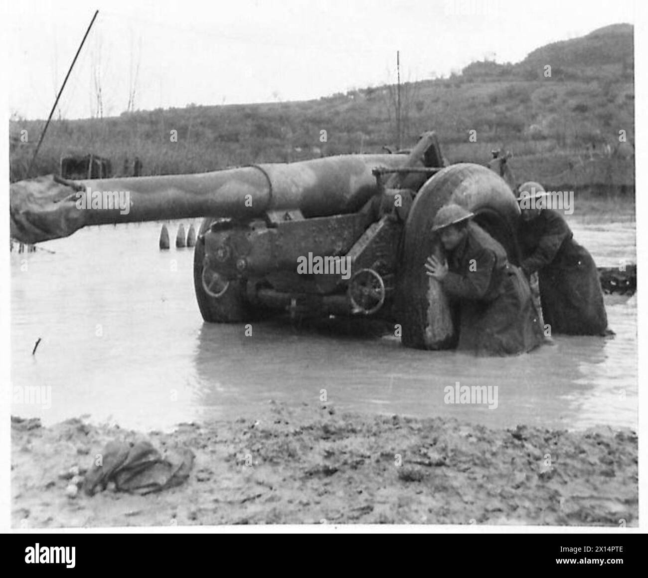 I membri dell'ottava armata britannica si assistono a vicenda in un sito allagato lungo il fiume Moro in Italia, illustrando il lavoro di squadra e le sfide operative in condizioni avverse. Foto Stock