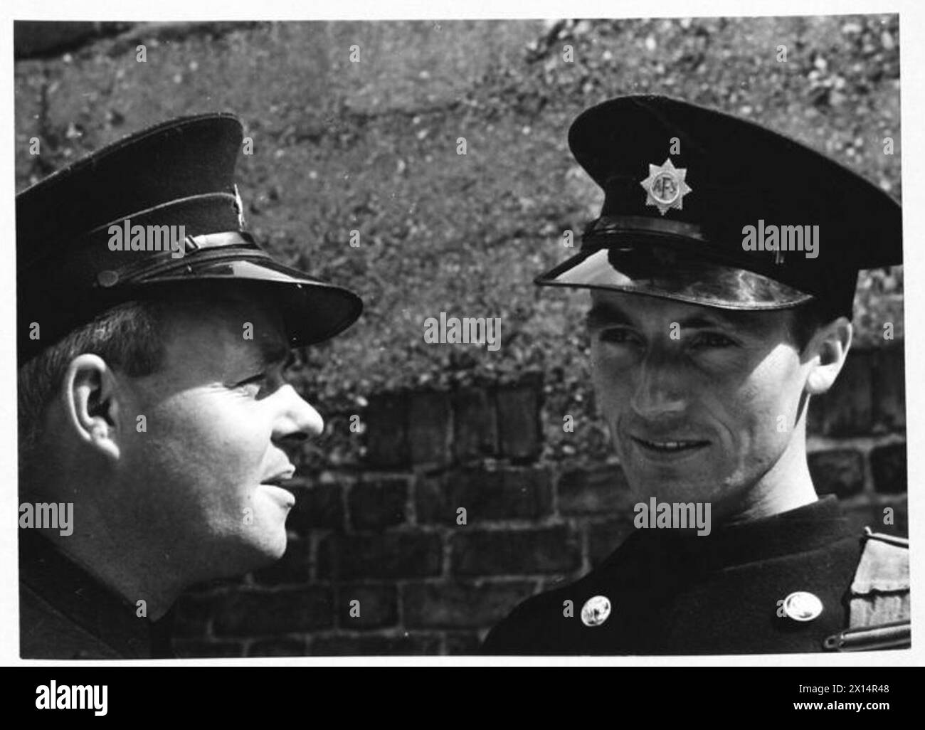 AFS FILM ACTORS: LE RIPRESE DI "STORIA INEDITA" AI DENHAM FILM STUDIOS, DENHAM, BUCKINGHAMSHIRE, INGHILTERRA, REGNO UNITO, 1941 - i piloti della Uxbridge Auxiliary Fire Service C Davidge (a sinistra) e M J Allaway (a destra) chiacchierano al sole dopo le riprese del film "Unpublished Story" della Two Cities Film Company. Il film è diretto da Harold French e interpretato da Richard Greene e Valerie Hobson. È ambientato durante il Blitz sui moli di Londra nel 1940. Secondo la didascalia originale, Allaway sta raccontando la storia del suo "essere 16" lontano da una bomba quando è caduta nel Tamigi" Foto Stock