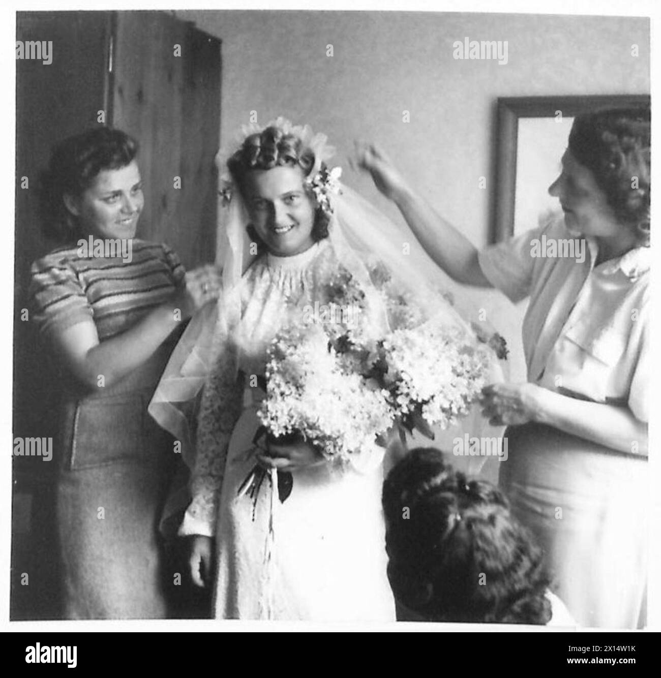 LA LIBERAZIONE DEL CAMPO DI CONCENTRAMENTO DI BERGEN-BELSEN, APRILE 1945 - amici della sposa aggiungendo il tocco finale al suo taglio di capelli, 21 luglio 1945. Una storia d'amore iniziata quando la commissione della Croce Rossa britannica entrò nel campo di Bergen-Belsen il 21 aprile 1945 culminò con il matrimonio del sig. Edward Quatrucci del 9 Waverley Way, Carshalton, Surrey, con la sig. Antonia Suchecka di Zakopane, nella Polonia meridionale, in una piccola chiesa del campo.il sig. Quatrucci, un soggetto britannico, era membro della commissione della Croce Rossa e ha svolto un lavoro prezioso nei primi giorni del campo di Belsen. Lì incontrò la signorina Suchecka, una detenuta della CA Foto Stock