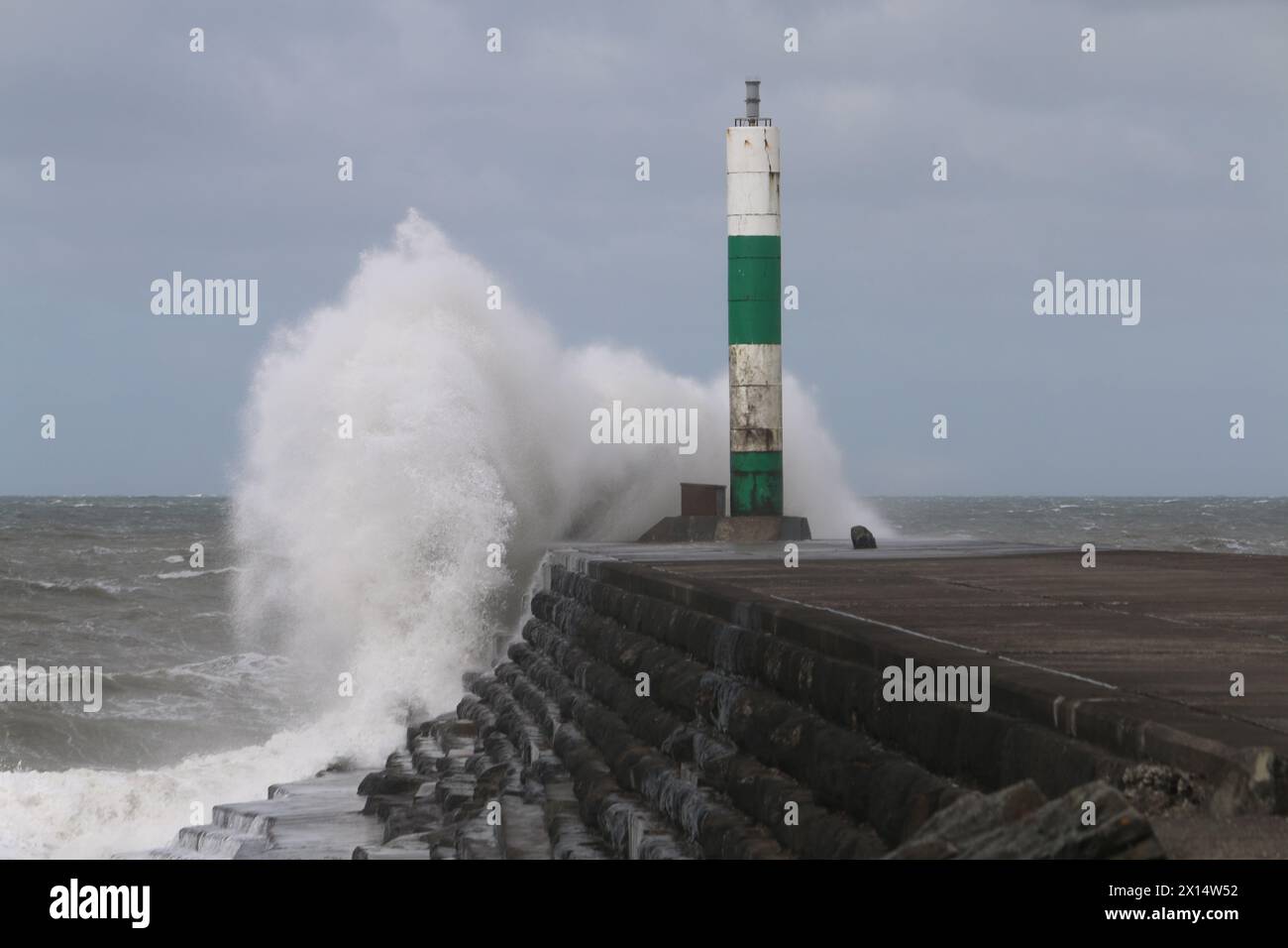 Aberystwyth Galles Regno Unito Meteo 15 aprile 2024. Forti venti di forte forza battono le zone costiere del Galles occidentale guidando in enormi onde che si schiantano contro la passeggiata e le difese portuali di Aberystwyth, credito: mike davies/Alamy Live News Foto Stock