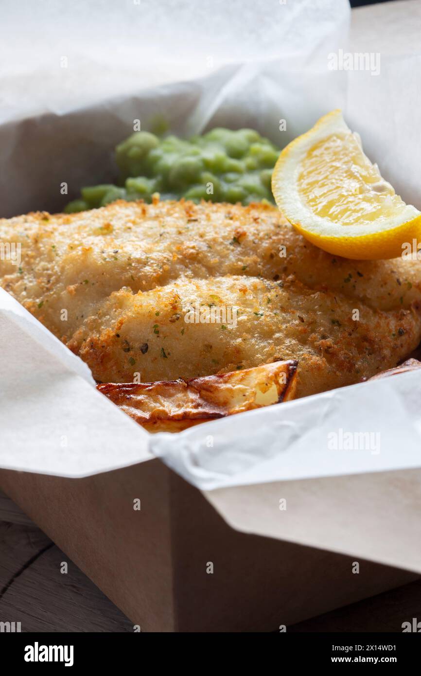 Takeaway di fish and chips con piselli di muschio e limone. Scatola di cartone da asporto ecologica, biodegradabile e priva di plastica. Foto Stock