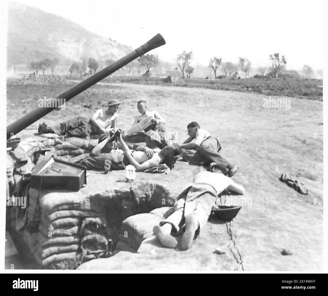 Il Gunner G. Gregg di Londra tiene d'occhio gli aerei nemici mentre i suoi compagni di soldati riposano al sole vicino alla caserma Bofors in Italia, sotto osservazione dell'esercito britannico. Foto Stock