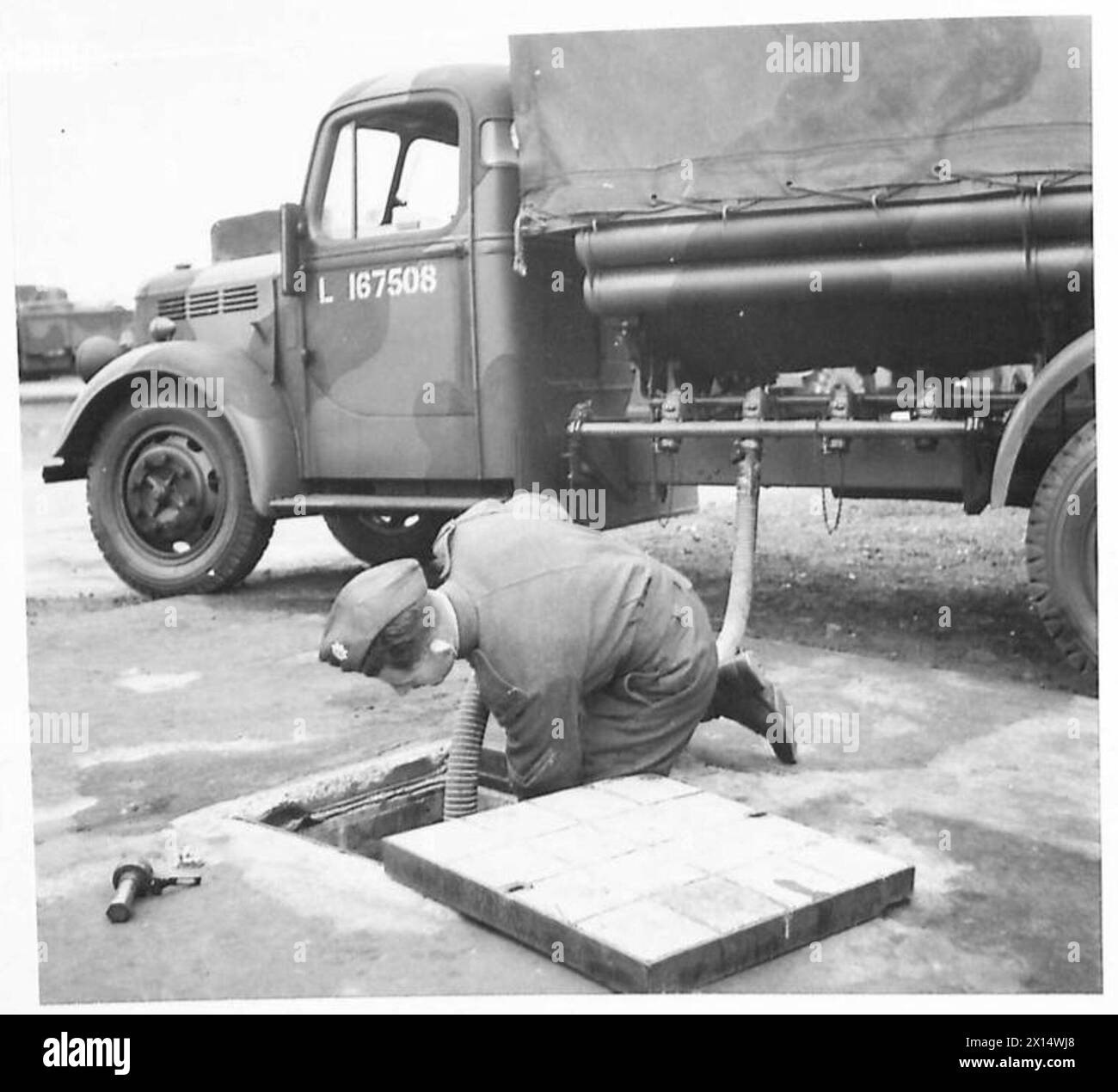 Un personale dell'esercito britannico collega un tubo flessibile da un autocarro a benzina sfuso a un pozzetto di entrata come parte delle operazioni di trasferimento del carburante. Foto Stock