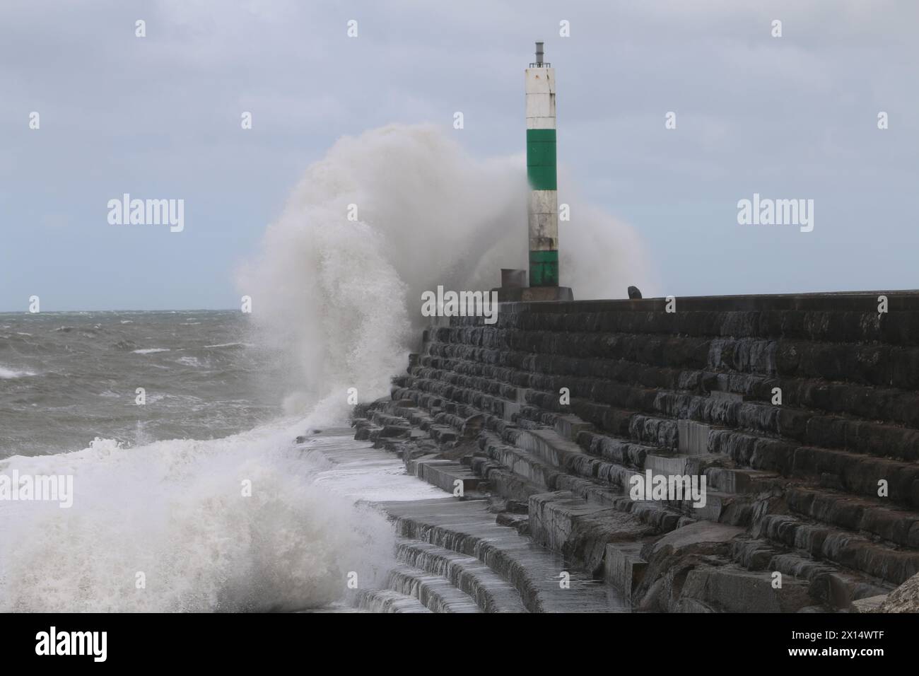 Aberystwyth Galles Regno Unito Meteo 15 aprile 2024. Forti venti di forte forza battono le zone costiere del Galles occidentale guidando in enormi onde che si schiantano contro la passeggiata e le difese portuali di Aberystwyth, credito: mike davies/Alamy Live News Foto Stock