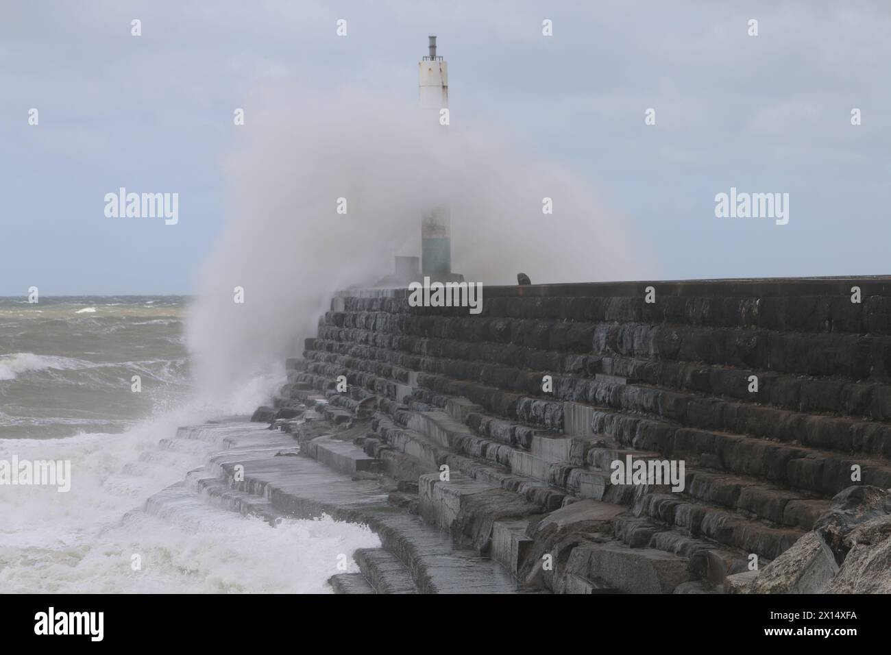 Aberystwyth Galles Regno Unito Meteo 15 aprile 2024. Forti venti di forte forza battono le zone costiere del Galles occidentale guidando in enormi onde che si schiantano contro la passeggiata e le difese portuali di Aberystwyth, credito: mike davies/Alamy Live News Foto Stock