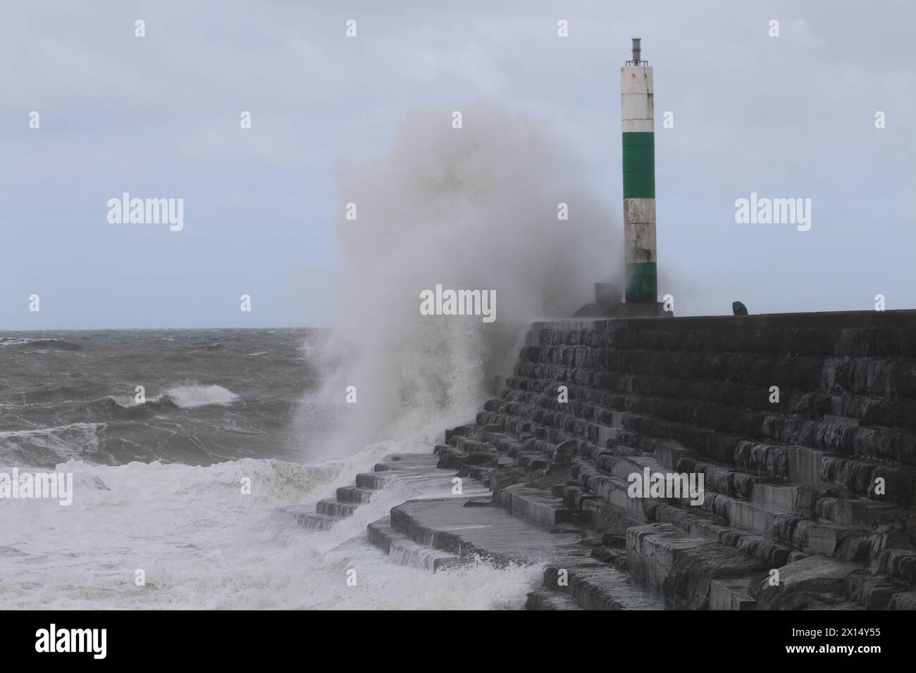 Aberystwyth Galles Regno Unito Meteo 15 aprile 2024. Forti venti di forte forza battono le zone costiere del Galles occidentale guidando in enormi onde che si schiantano contro la passeggiata e le difese portuali di Aberystwyth, credito: mike davies/Alamy Live News Foto Stock