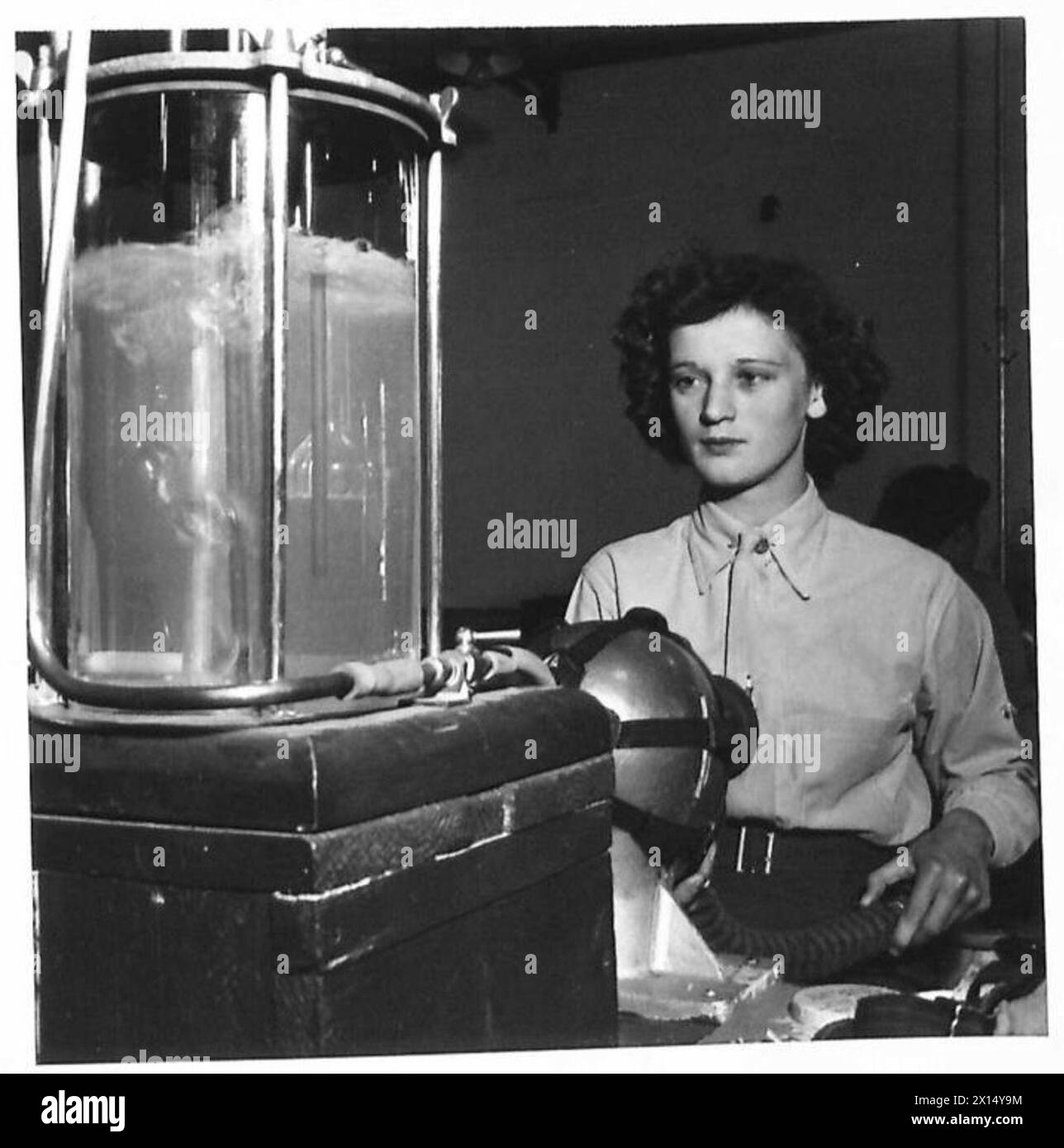 Un ausiliario ATS utilizza uno strumento specializzato per testare le facciate del respiratore per verificare la presenza di perdite, illustrando la manutenzione e il controllo di qualità dei dispositivi di protezione da parte dell'esercito britannico. Foto Stock