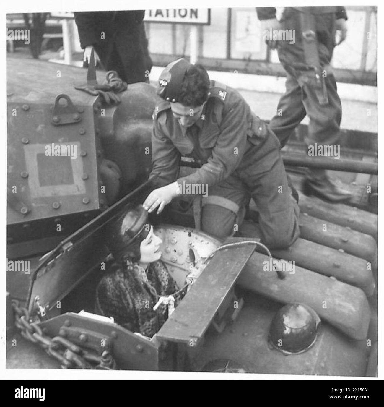 Gli operai osservano i carri armati militari e salgono su alcuni veicoli per esaminare gli interni, mostrando interesse per la costruzione e il design. Foto Stock