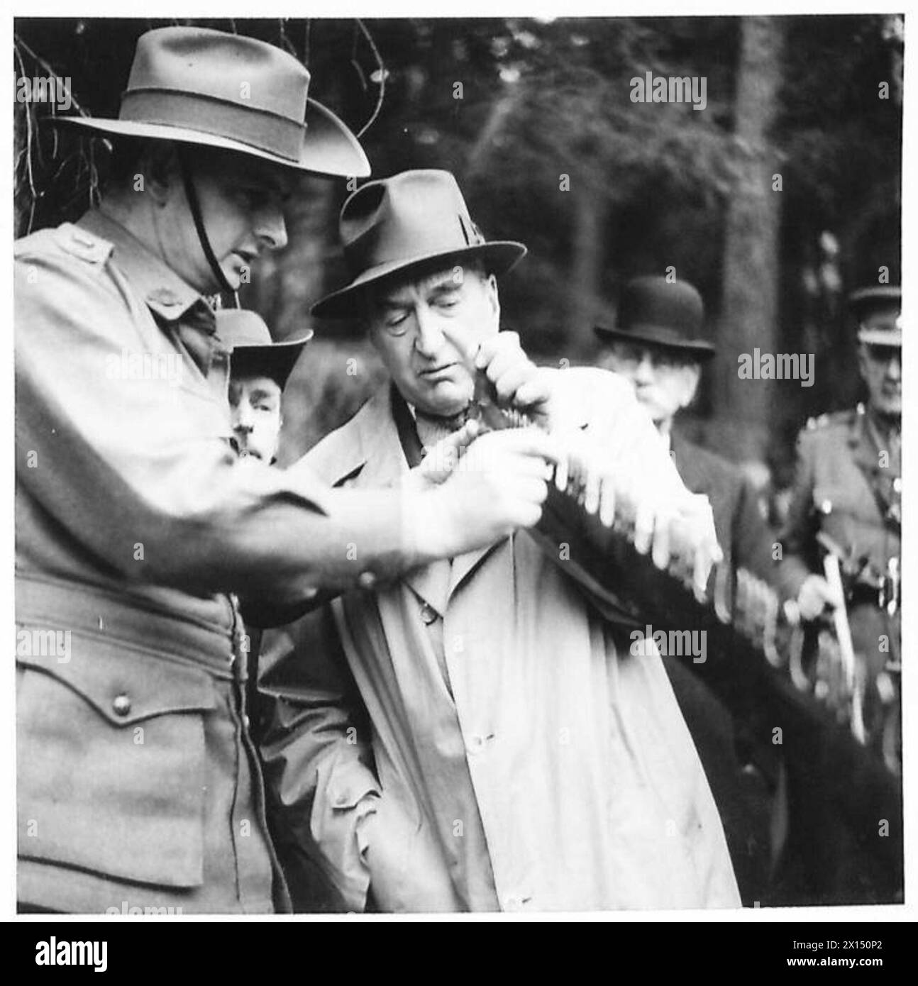 S.M. Bruce ispeziona i legnami australiani ed esamina il bordo di una grossa sega durante una visita in Scozia sotto la supervisione dell'esercito britannico. Foto Stock