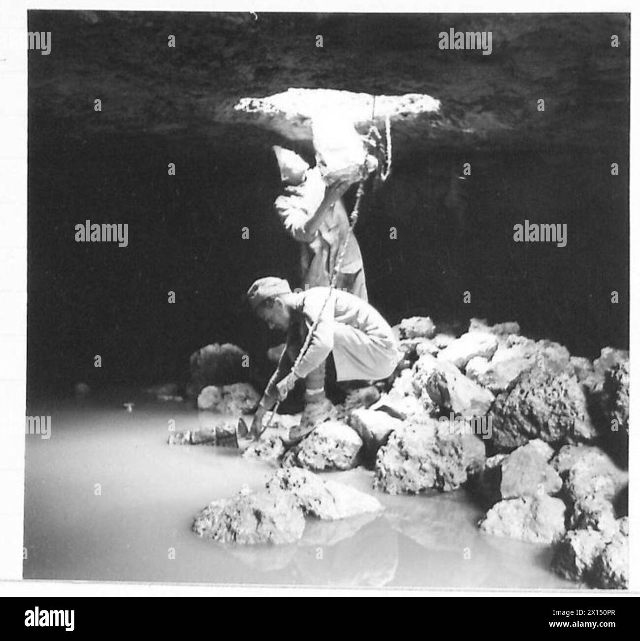 Un convoglio d'acqua nel deserto utilizza un salpanino fatto in casa per trasportare l'acqua da un profondo buco, illustrando le operazioni di approvvigionamento e logistica. Foto Stock