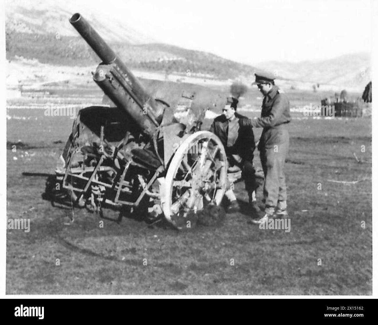 L'ESERCITO BRITANNICO IN NORD AFRICA, SICILIA, ITALIA, BALCANI E AUSTRIA 1942-1946 - il secondo cannone da 105 mm catturato, irreparabilmente danneggiato da un colpo diretto da un proiettile da 25 libbre. BSM Lomas e Lieut. Dawes di Westbury-on-Tryon, Bristol, esaminano il cannone danneggiato dell'esercito britannico Foto Stock