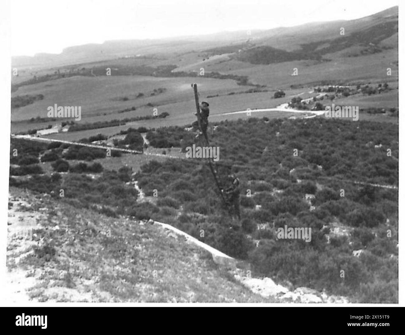 I segnalatori dell'esercito britannico gestiscono linee di comunicazione attraverso il terreno rurale, illustrando il dispiegamento e il lavoro tecnico nelle operazioni sul campo. Foto Stock