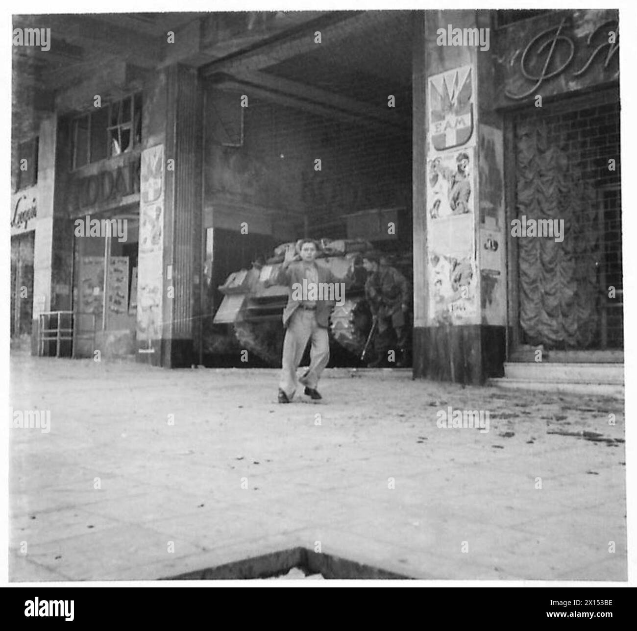 Durante la guerra civile greca, un prigioniero con le mani alzate esce dall'edificio E.A.M. L'evento riflette la detenzione militare e le operazioni di conflitto durante le ostilità interne. Foto Stock