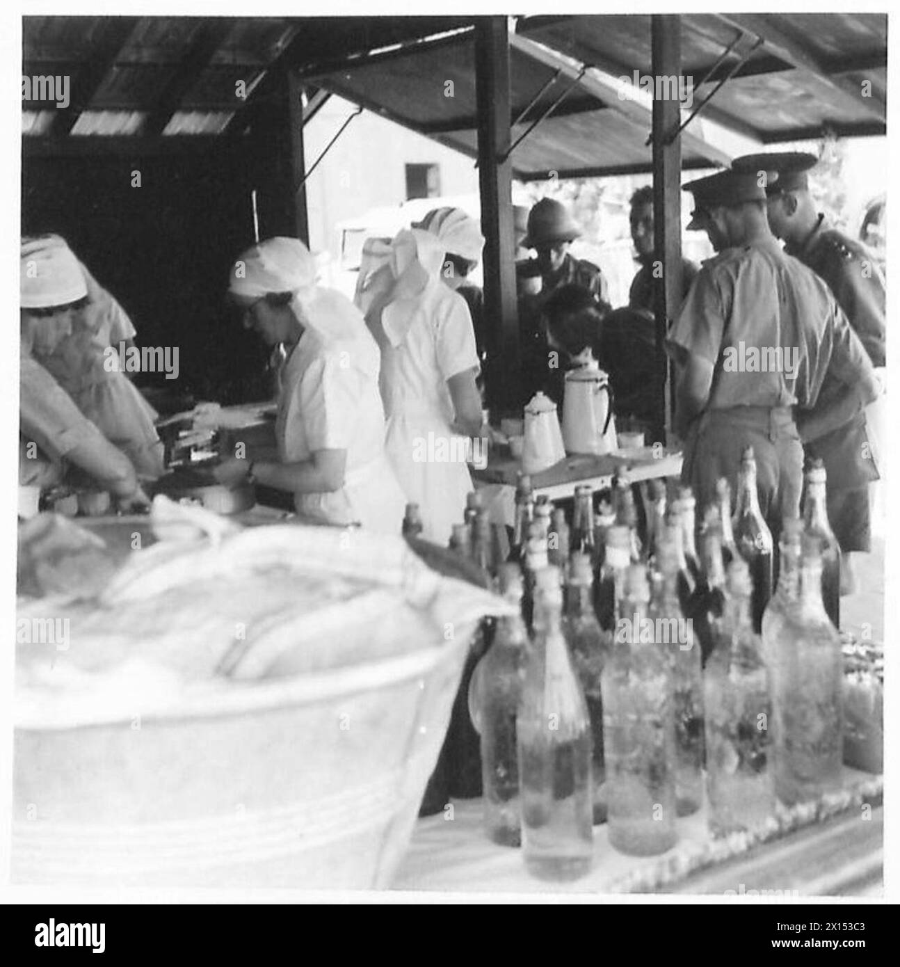 I lavoratori volontari forniscono bevande rinfrescanti ai soldati in una mensa sul molo, sostenendo il personale militare nelle operazioni logistiche e assistenziali. Foto Stock