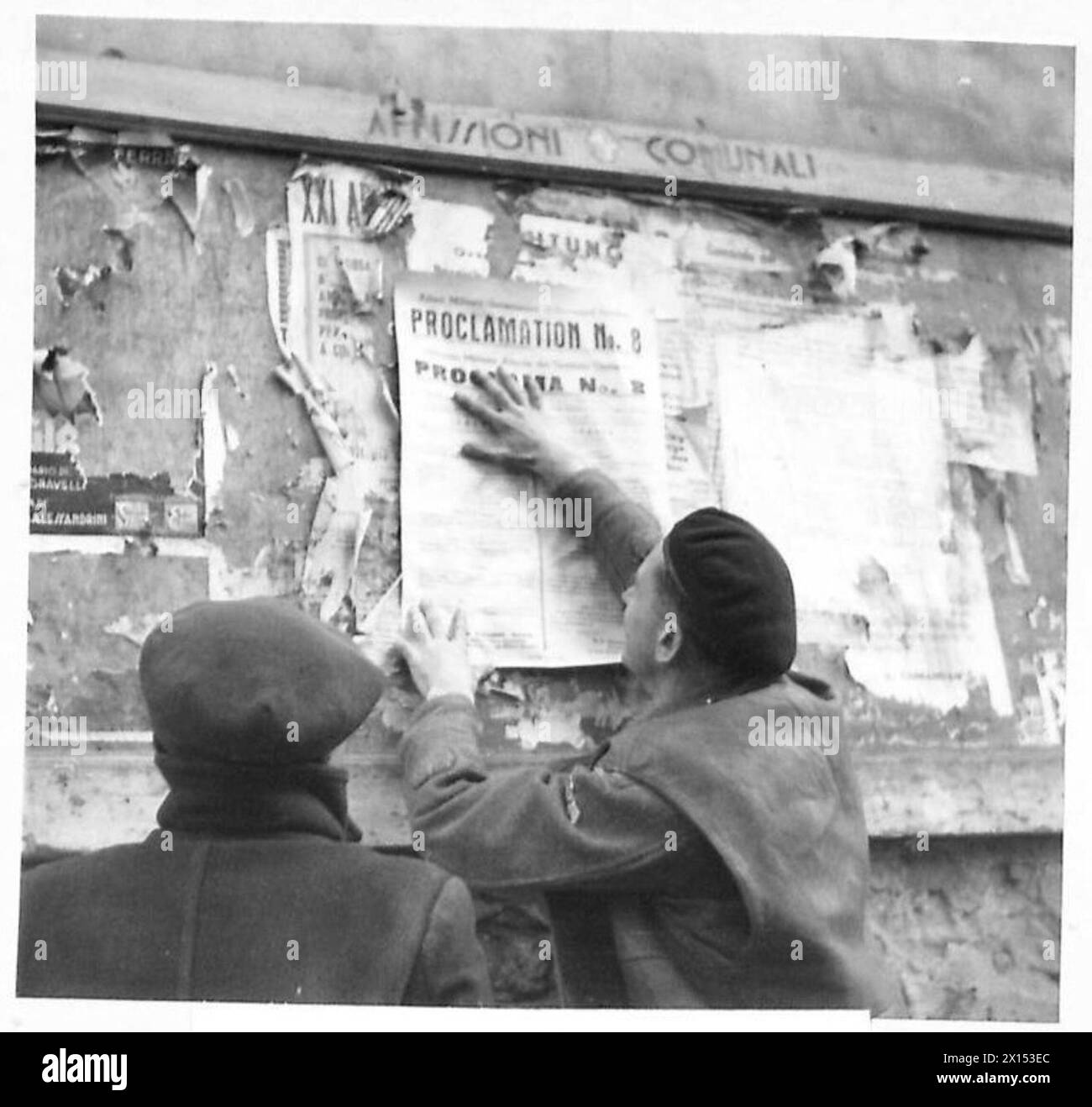 In una città di guarnigione italiana, il sergente maggiore T. Hague pubblica una nuova proclamazione su un poster tedesco come parte dei cambiamenti amministrativi sotto AMGOT. Foto Stock