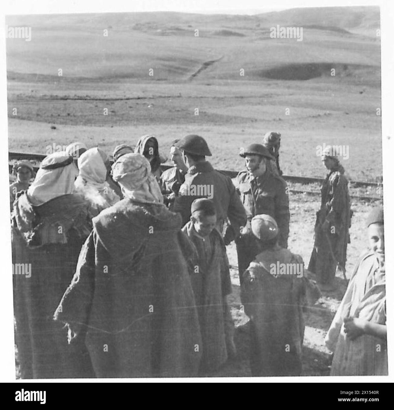 THE BRITISH IN THE TUNISIA CAMPAIGN, NOVEMBRE 1942-MAGGIO 1943 - gruppo di locali interrogati dalla polizia di sicurezza sul campo. Il villaggio di Guernina è stato razziato dalla sezione di polizia di sicurezza sul campo della 36th Infantry Brigade (78th Division) poiché gli abitanti erano sospettati di accumulare armi e munizioni per il nemico. Tuttavia, non è stato trovato nulla e i nativi durante l'ispezione erano gentili e disponibili. In considerazione di ciò si decise di inviare regali agli abitanti del villaggio come segno di apprezzamento e anche di sponsorizzare la buona volontà tra la popolazione britannica e quella araba. 19 Foto Stock