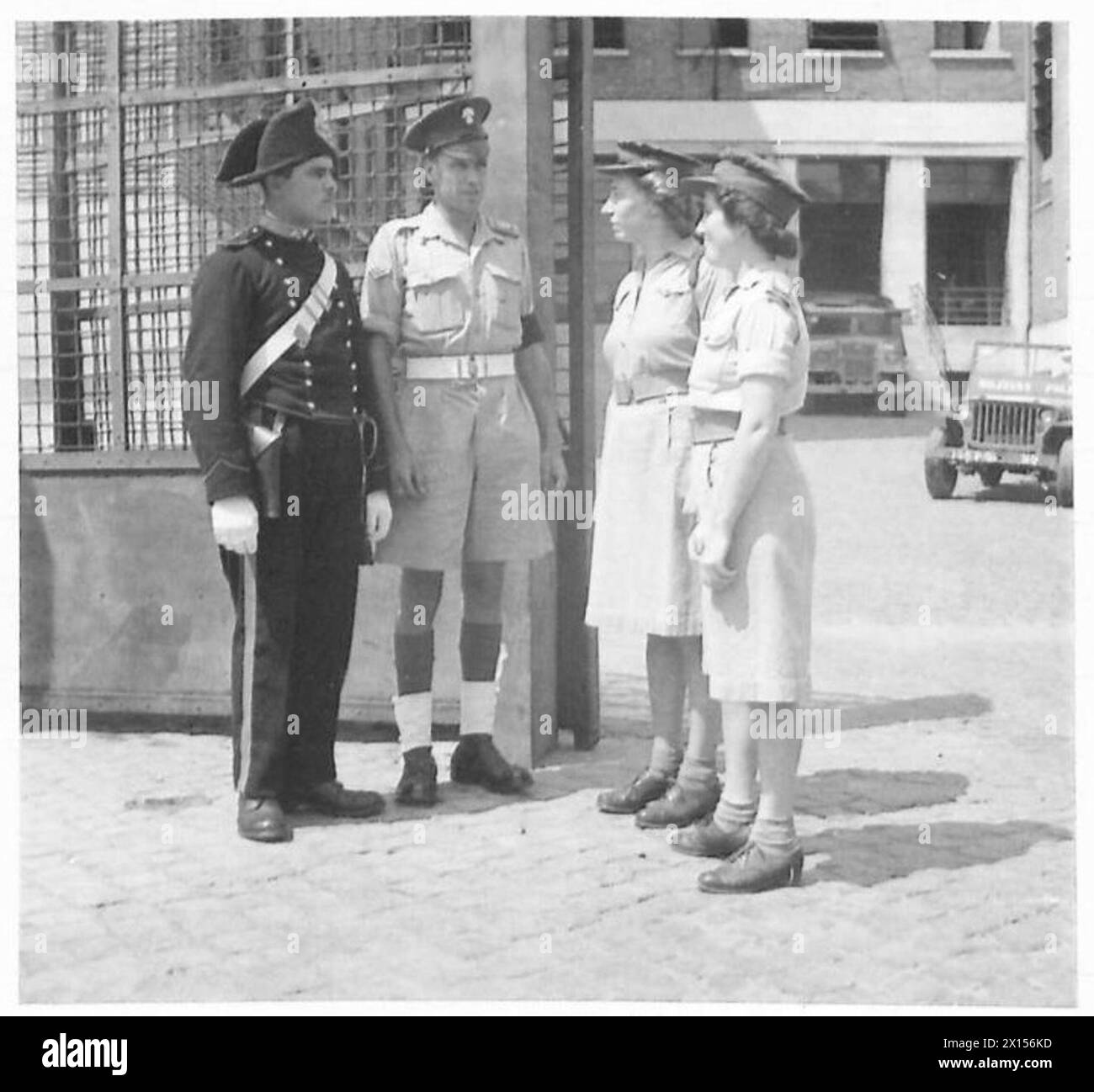 Due membri del servizio territoriale ausiliario di Dublino parlano con un carabinieri italiano e un ufficiale di polizia militare all'ingresso degli edifici amministrativi in Italia durante il servizio dell'esercito britannico. Foto Stock