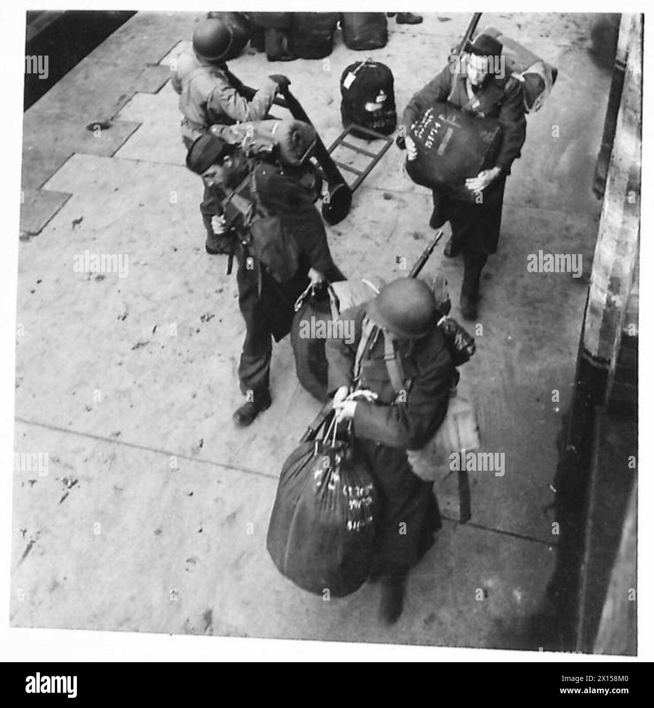 Le truppe americane e britanniche trasportano borse e attrezzature sulla banchina durante le operazioni dell'esercito britannico. Foto Stock