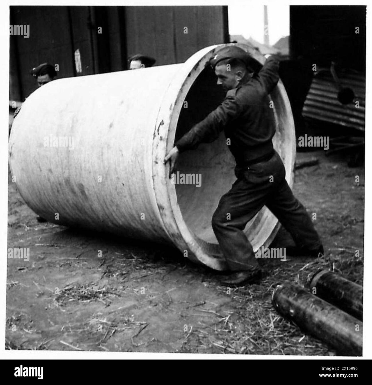 Il personale del Pioneer Corps assiste nello scarico di tubi in cemento armato presso una banchina come parte delle operazioni logistiche dell'esercito britannico. Foto Stock