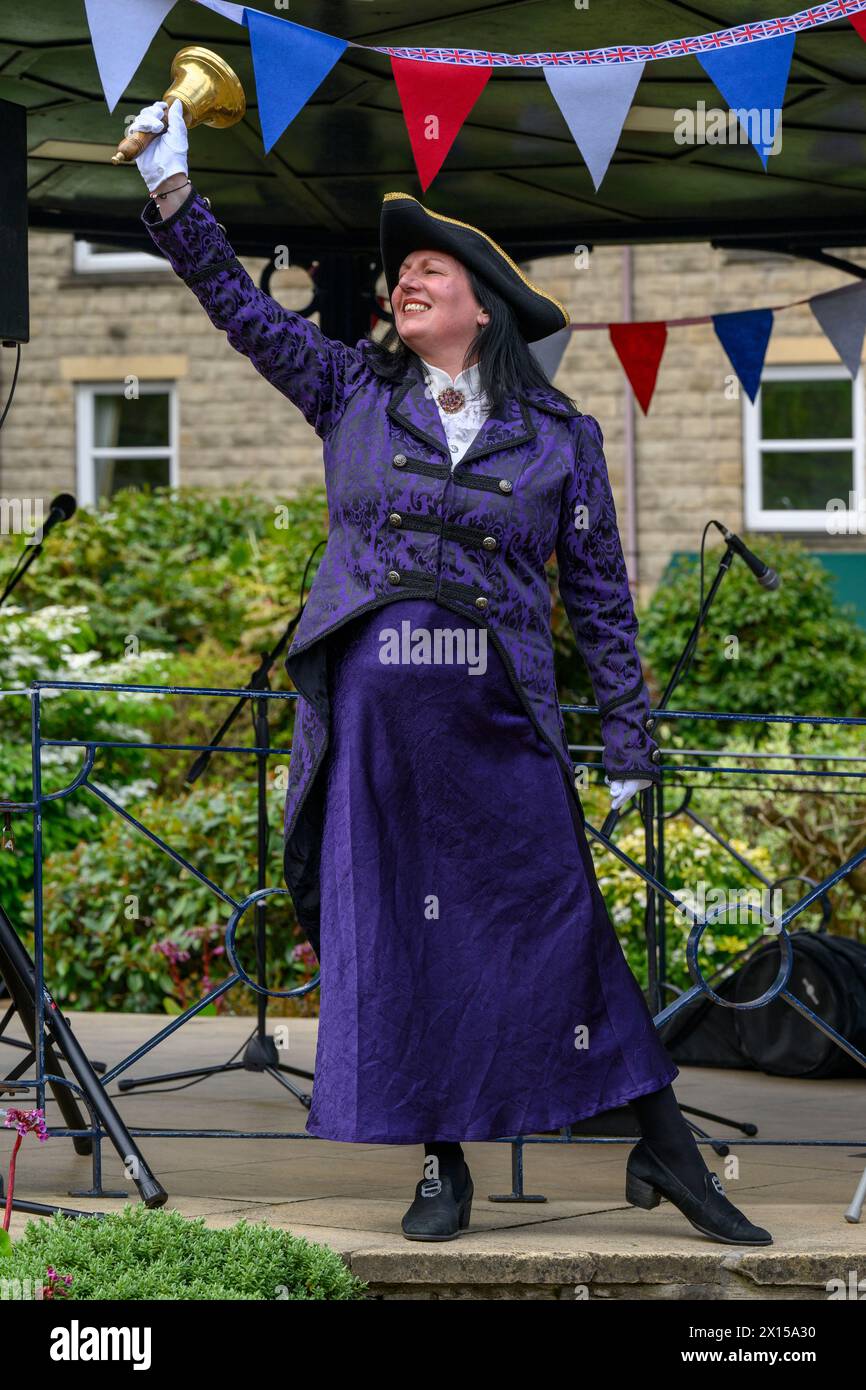 Donna pigriera e cameriera (abiti da livrea da donna) che fa annunci e annunci pubblici rumorosi - Ilkley, West Yorkshire, Inghilterra Regno Unito. Foto Stock