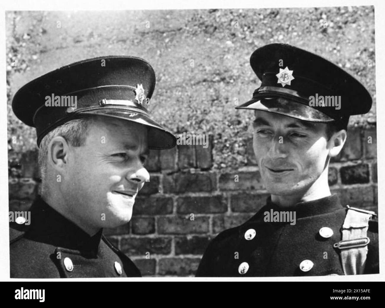 AFS FILM ACTORS: LE RIPRESE DI "STORIA INEDITA" AI DENHAM FILM STUDIOS, DENHAM, BUCKINGHAMSHIRE, INGHILTERRA, REGNO UNITO, 1941 - i piloti della Uxbridge Auxiliary Fire Service C Davidge (a sinistra) e M J Allaway (a destra) chiacchierano al sole dopo le riprese del film "Unpublished Story" della Two Cities Film Company. Il film è diretto da Harold French e interpretato da Richard Greene e Valerie Hobson. È ambientato durante il Blitz sui moli di Londra nel 1940. Secondo la didascalia originale, Allaway sta raccontando la storia del suo "essere 16" lontano da una bomba quando è caduta nel Tamigi" Foto Stock