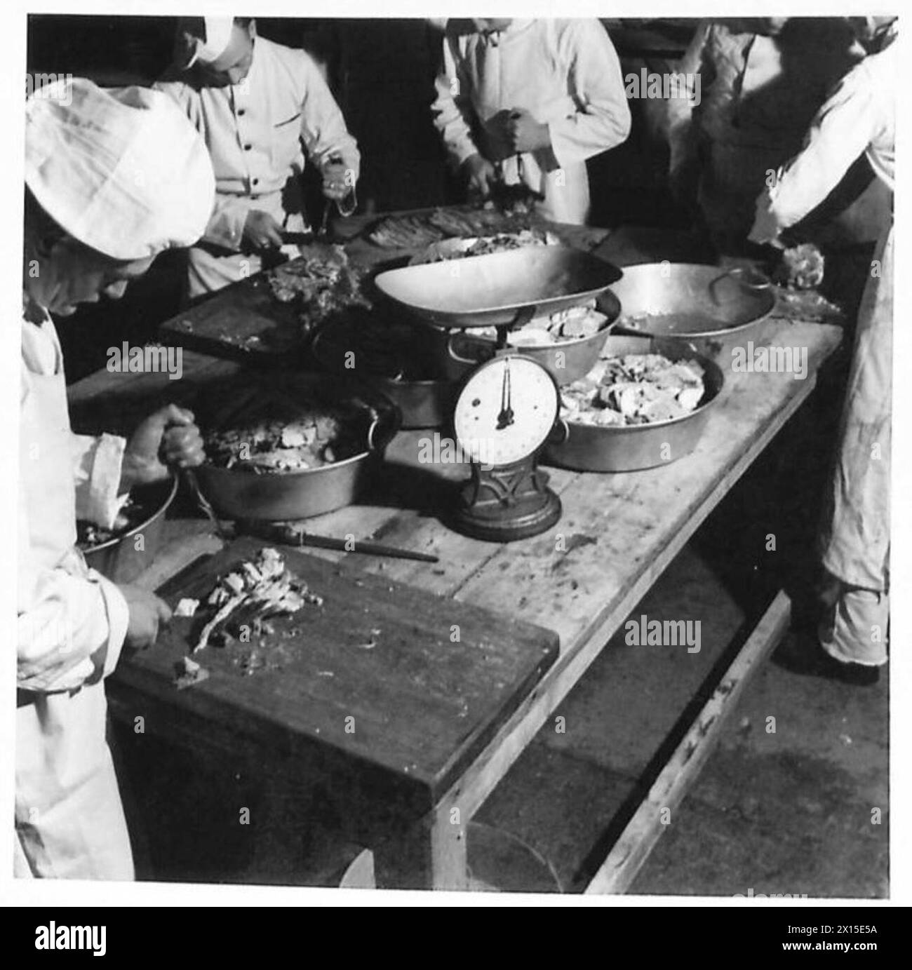 I cuochi dell'esercito di un battaglione delle guardie scozzesi affettano carne cucinata a un tavolo di intaglio per le truppe durante l'ora dei pasti. Foto Stock