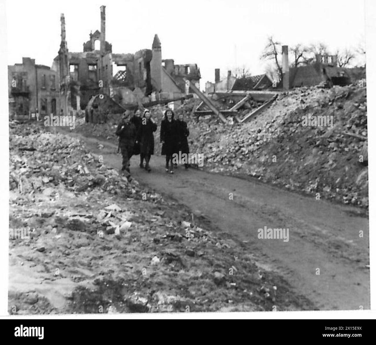 I civili camminano per le strade di Stadtlohn dopo essere stati rilasciati dai lavori forzati a seguito dei bombardamenti della città. Foto Stock