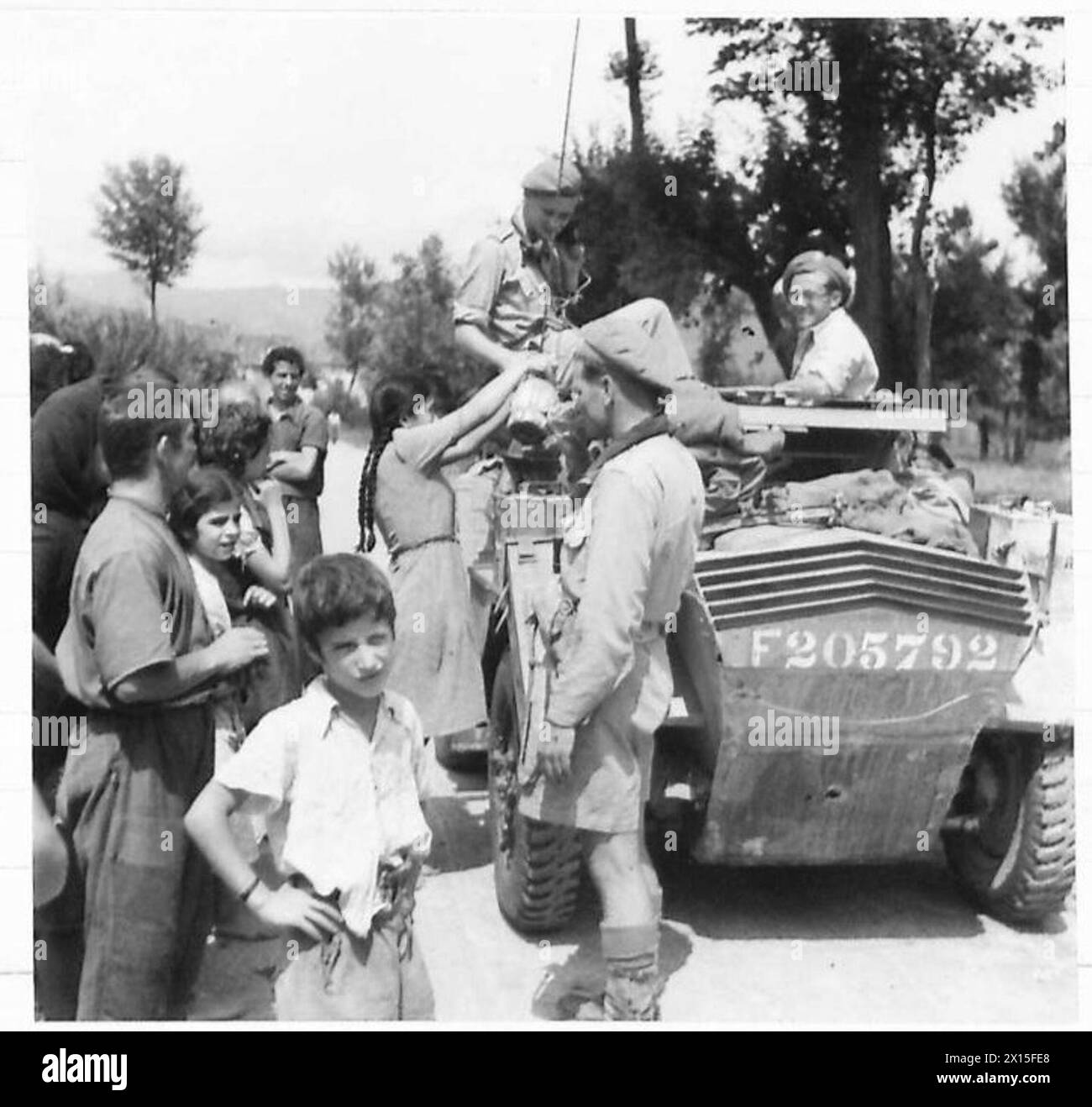 Un'auto da ricognizione dell'Ottava Armata si ferma vicino a una fattoria nella Terra di No Man, dove gli italiani danno un caloroso benvenuto, illustrando l'interazione con i civili locali durante le operazioni. Foto Stock