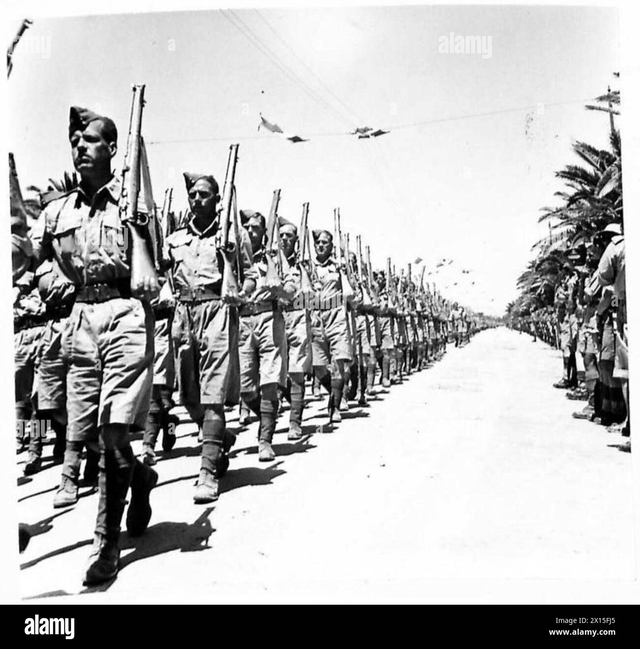 Le truppe britanniche marciano in una parata di vittorie a Tunisi, celebrando la fine delle operazioni militari e mostrando uniformi e formazioni reggimentali. Foto Stock