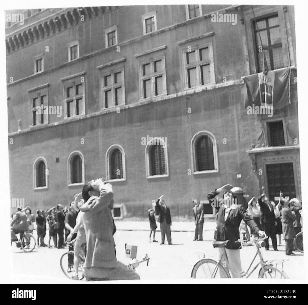 I civili stanno fuori da Palazzo Venezia osservando i primi aerei alleati volare sopra la città dopo la liberazione. Foto Stock