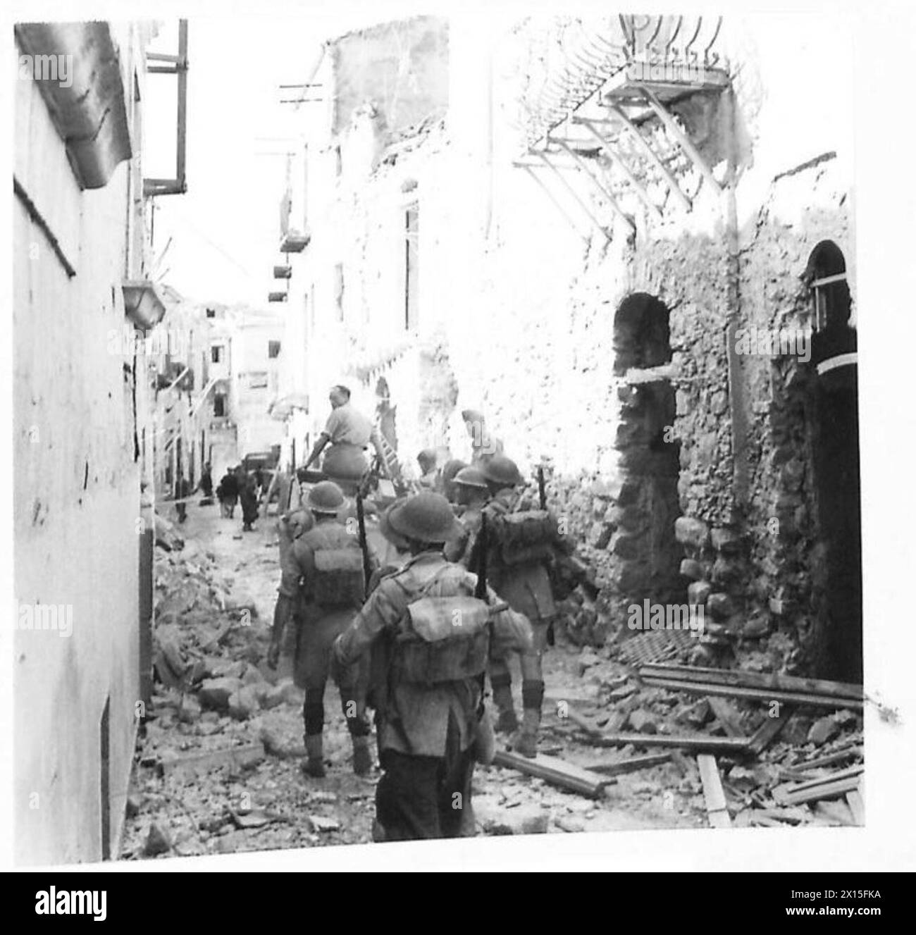 La fanteria britannica segue un vettore Bren attraverso una stretta strada cittadina durante le operazioni della seconda guerra mondiale in Nord Africa, Sicilia, Italia, Balcani e Austria. La scena raffigura le sfide della guerra urbana e il coordinamento tra fanteria e supporto corazzato. Foto Stock