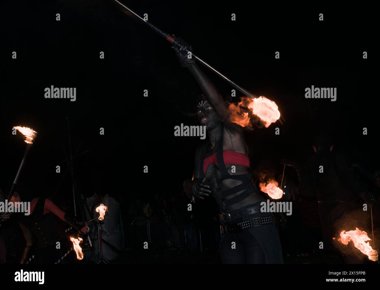 ballerini di fuoco con un bastone acceso ad ogni estremità che torce il fuoco che perfora la notte Foto Stock