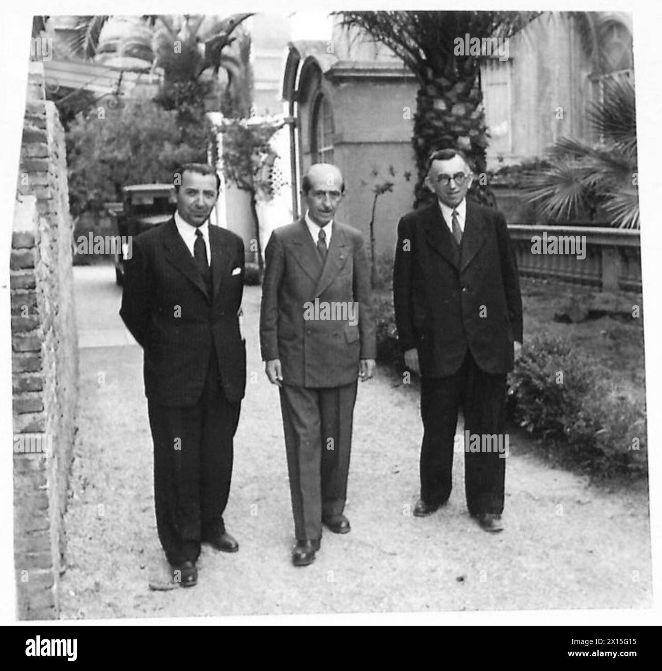 Gli esuli albanesi camminano nel giardino di un hotel dopo la liberazione da parte delle forze alleate: Il professor Frano Karma, un prete cattolico, l'ex ministro Mehmet Konitza, e il dottor Hikmet Mece, ex giudice e sindaco, British Army. Foto Stock