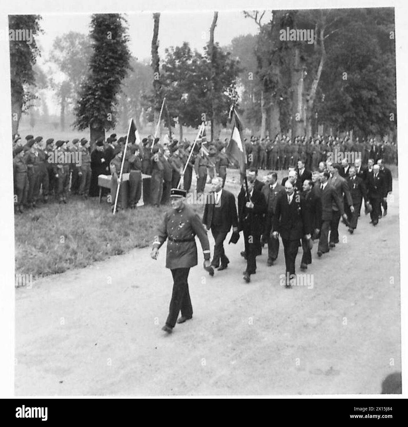 I membri dell'Amfreville Old Comrades Association marciano oltre la base salutista in Normandia a seguito di un servizio del giorno della Bastiglia sotto il 21st Army Group britannico. Foto Stock
