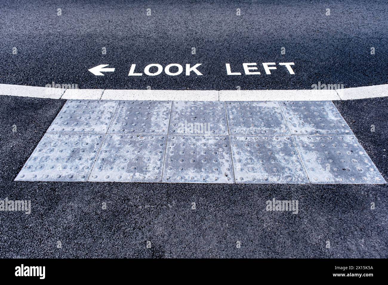 Guarda a sinistra quando attraversi la strada, informazioni sul traffico per i pedoni dipinti su asfalto nel Regno Unito Foto Stock