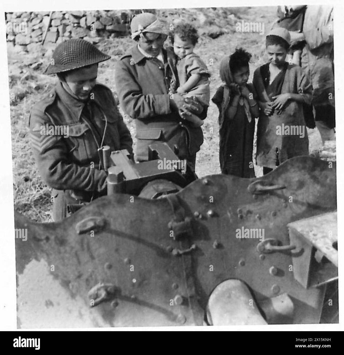 Sergente della 255th Battery, Royal Artillery si trova accanto a un cannone anticarro da sei libbre sulle colline vicino a Medjez el Bab il 31 dicembre 1942, con spettatori arabi e bambini che guardano. Foto Stock