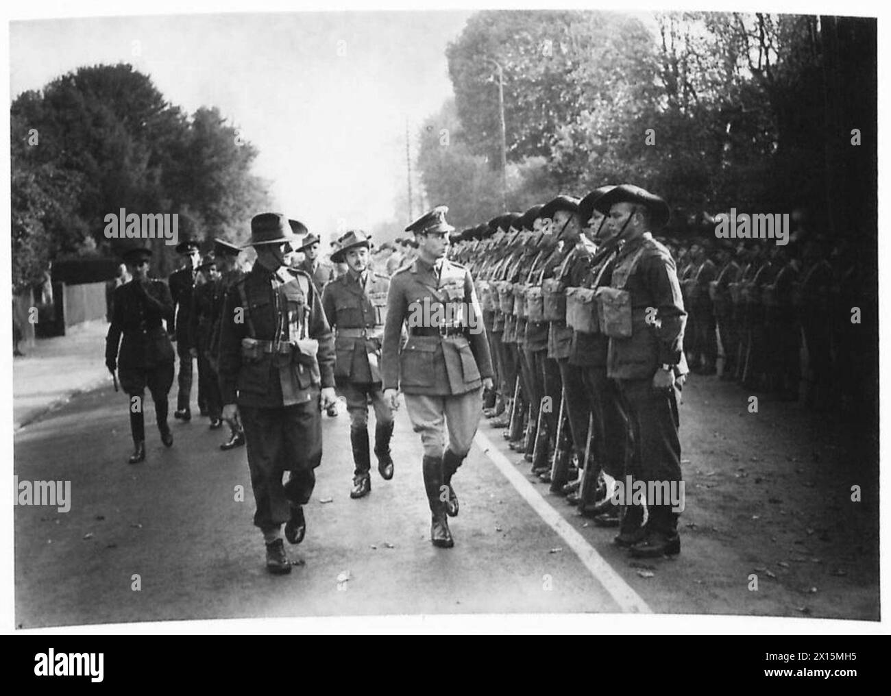 Sua Maestà il Re ispeziona le truppe australiane durante una visita formale, osservando le loro formazioni e la loro prontezza. Foto Stock