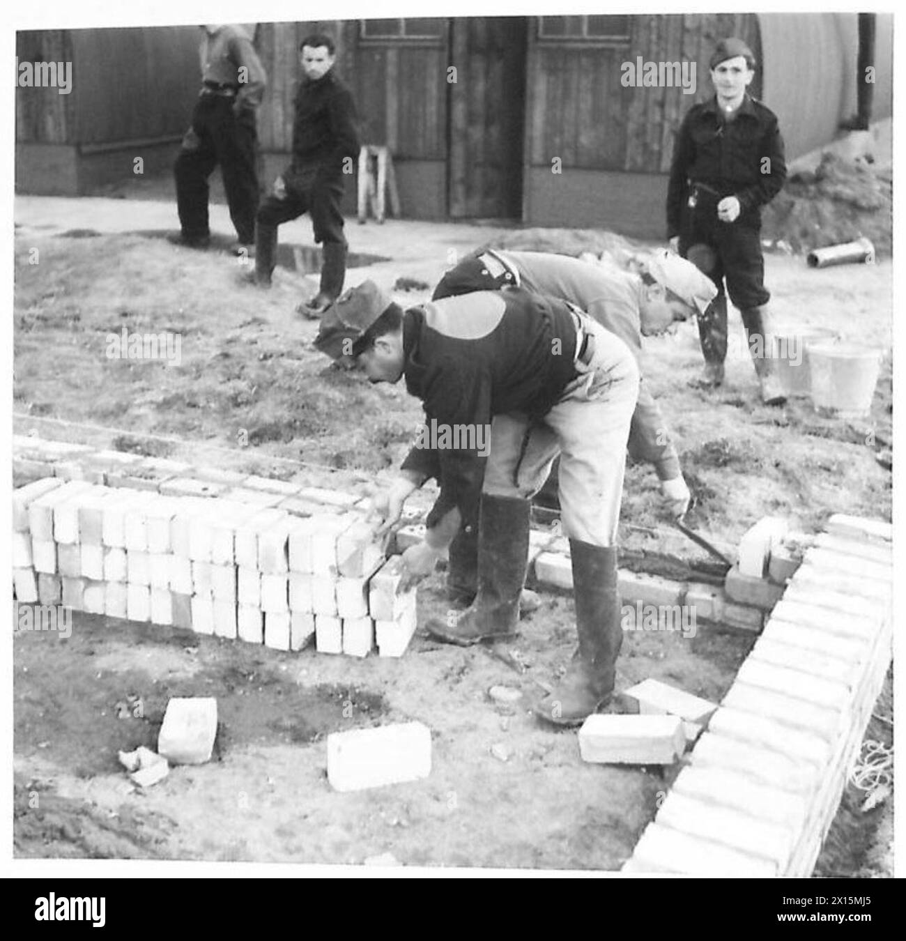 I prigionieri di guerra italiani stanno costruendo i loro quartieri invernali sotto la supervisione di un campo durante la seconda guerra mondiale, con il sostegno dell'esercito britannico. Foto Stock
