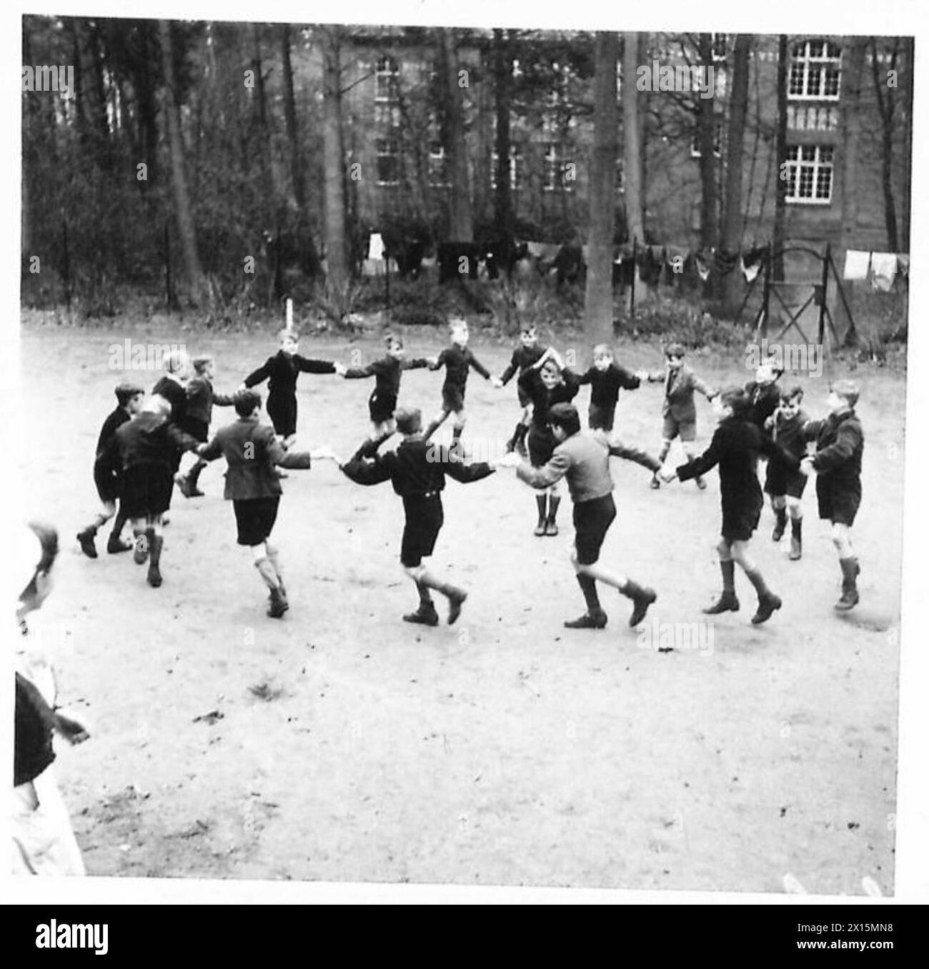 I bambini tedeschi sotto il governo militare sono curati da infermiere e sorelle addestrate durante il giorno. Si osservano giocare a Kreisspiel, un tradizionale gioco a cerchio. La supervisione è fornita dal British Army, 21st Army Group. Foto Stock