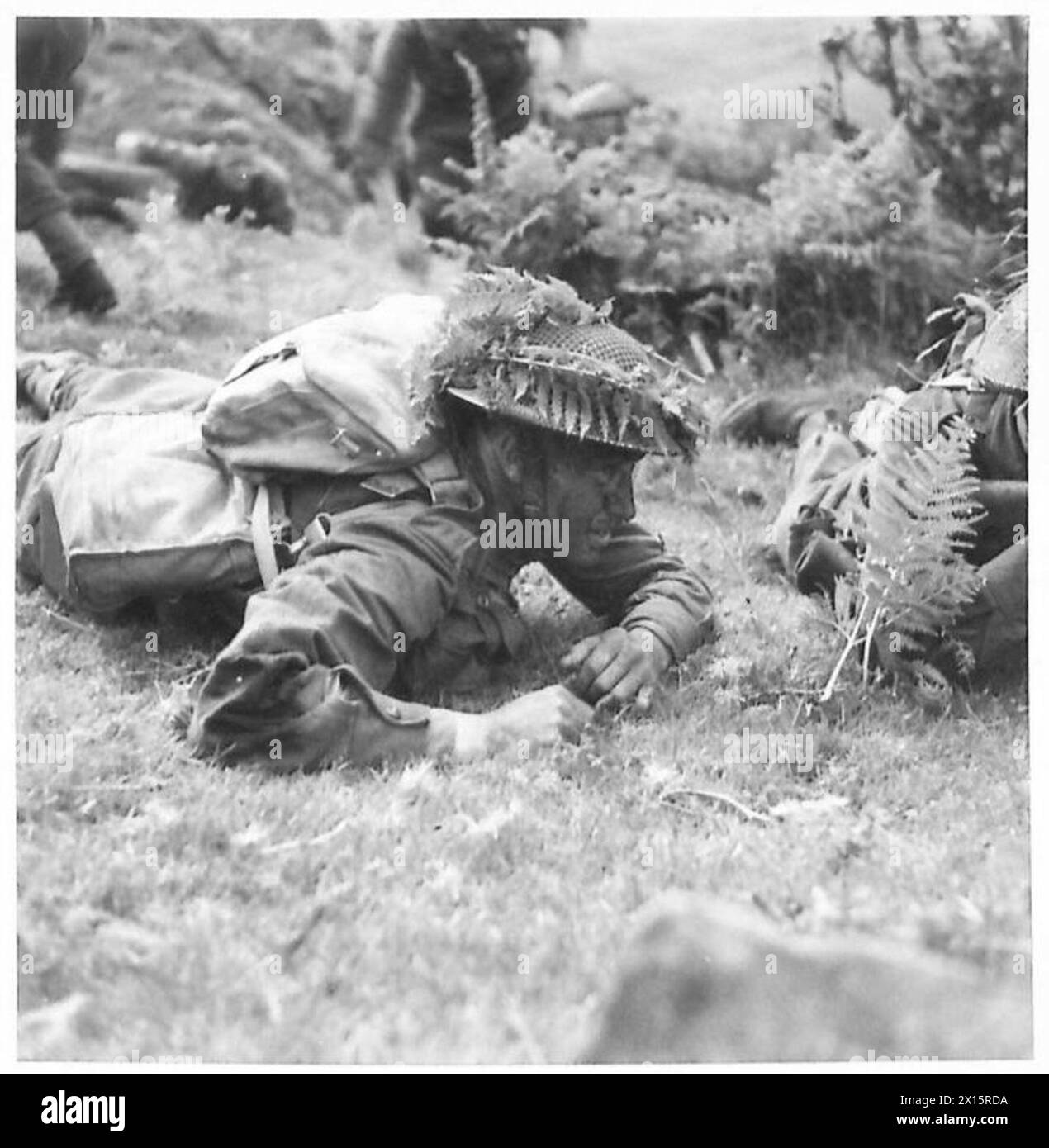 I soldati con facce annerite e caschi in acciaio mimetizzati si muovono cautamente verso gli obiettivi durante gli esercizi presso una British Army Battle School. Foto Stock