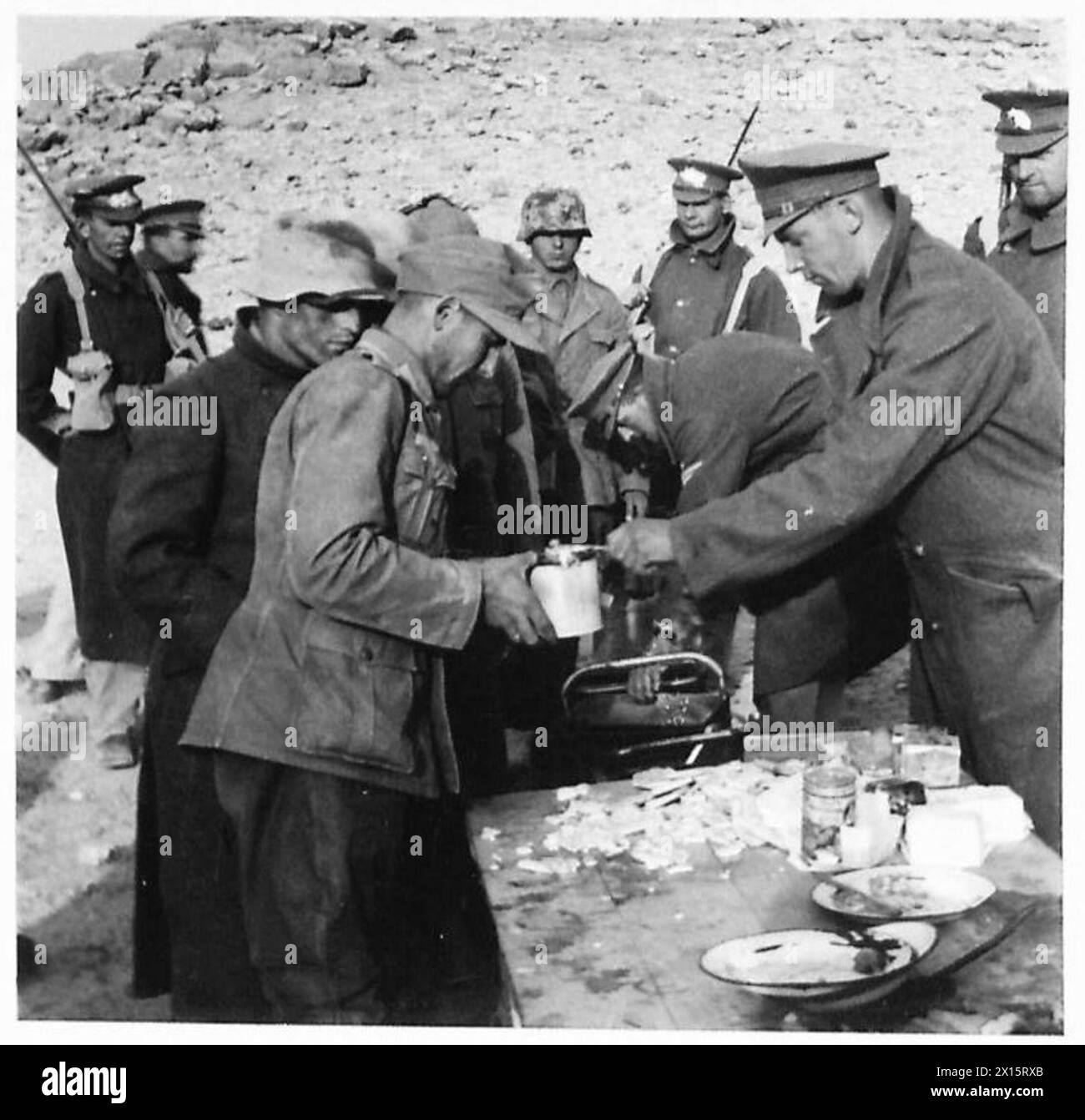 I prigionieri tedeschi catturati nel deserto occidentale ricevono la colazione dalle truppe britanniche a causa della mancanza di cibo. Foto Stock