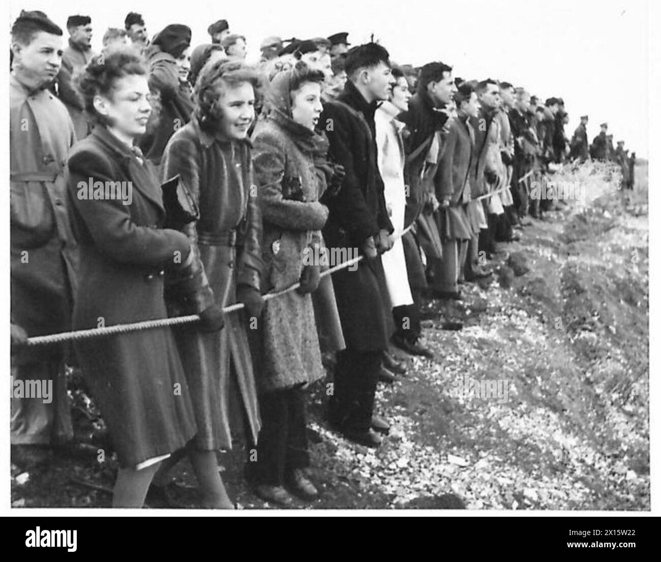 Una grande folla di spettatori osserva una dimostrazione di armi militari, mostrando l'uso di armi da fuoco e artiglieria in un ambiente controllato. Foto Stock