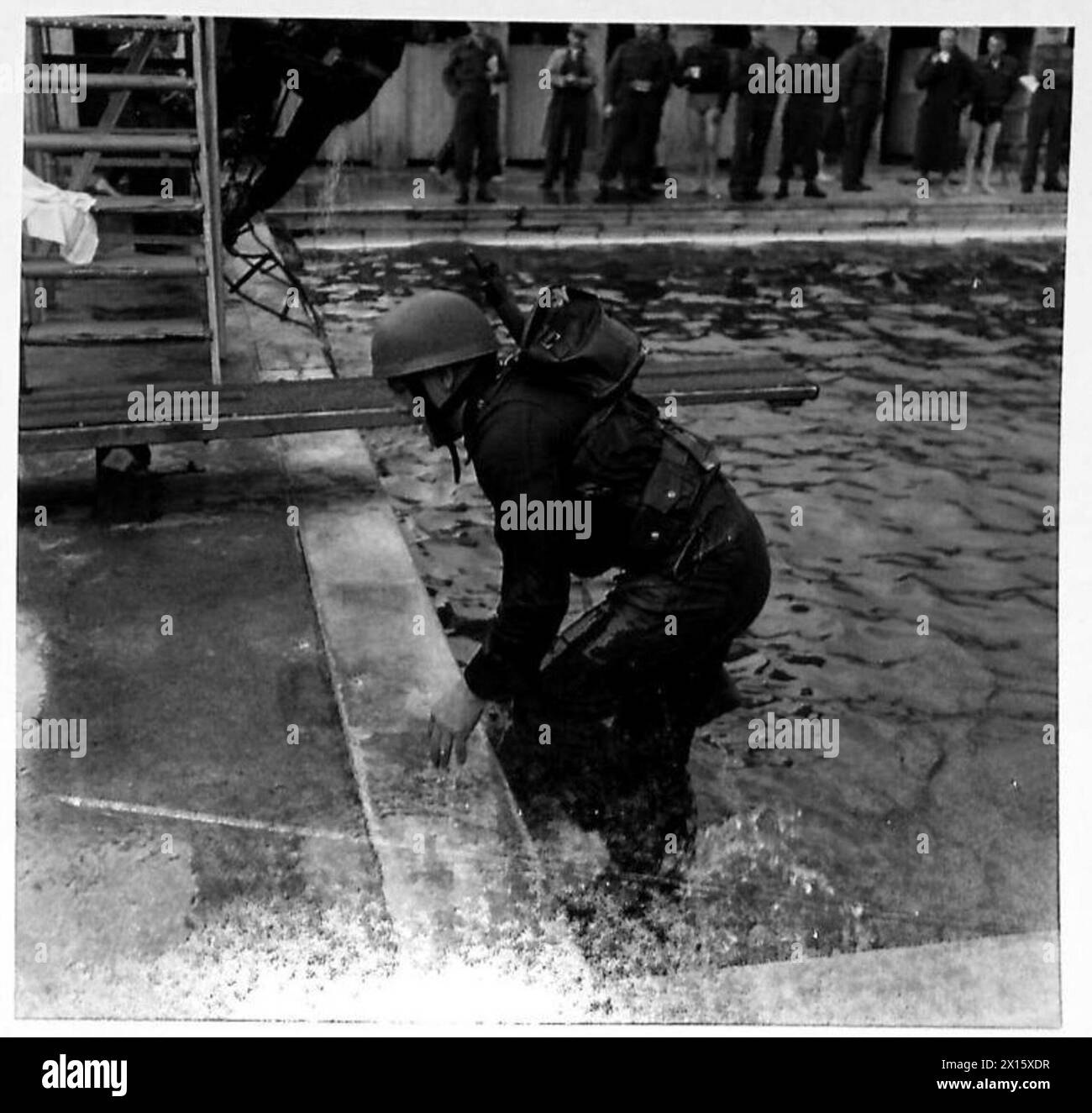 Gli uomini nuotano per tutta la lunghezza del bagno con il kit completo, guadagnando peso dall'attrezzatura, e salgono una scala di corda dopo aver completato la nuotata. Foto Stock