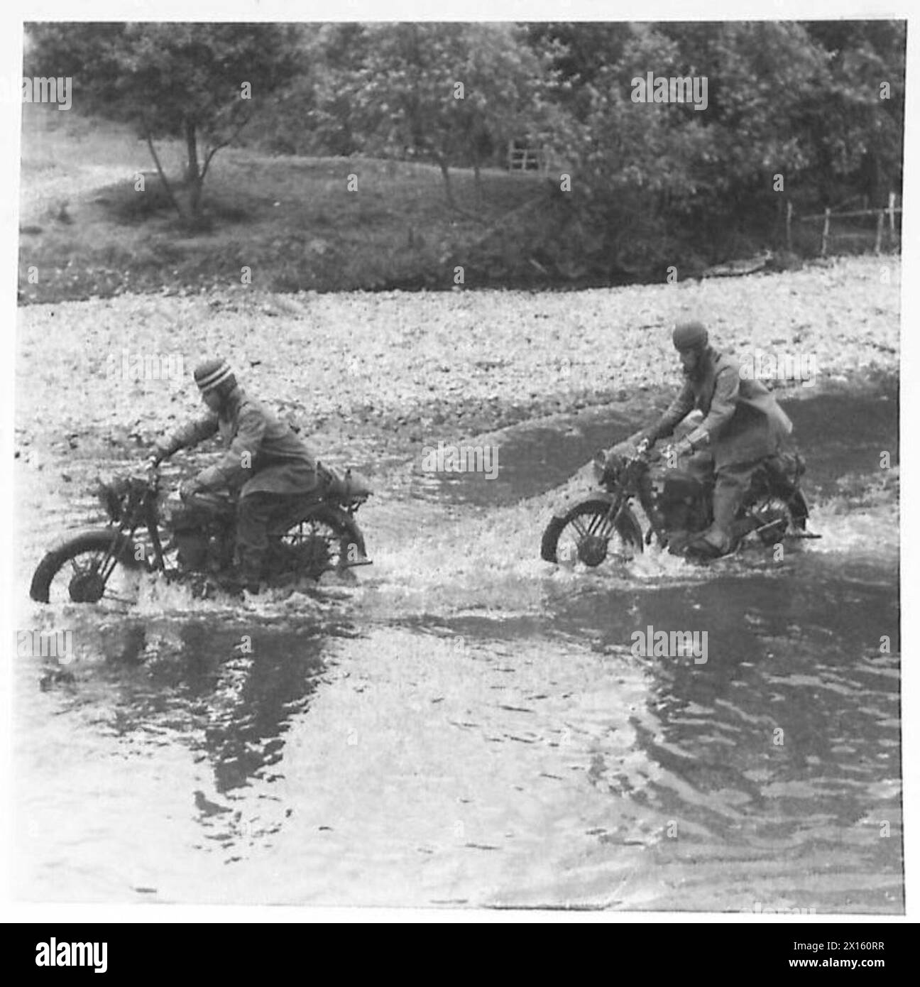 I conducenti della Royal Artillery esercitano a guidare motociclette attraverso un ruscello come parte dei loro esercizi di allenamento. Foto Stock