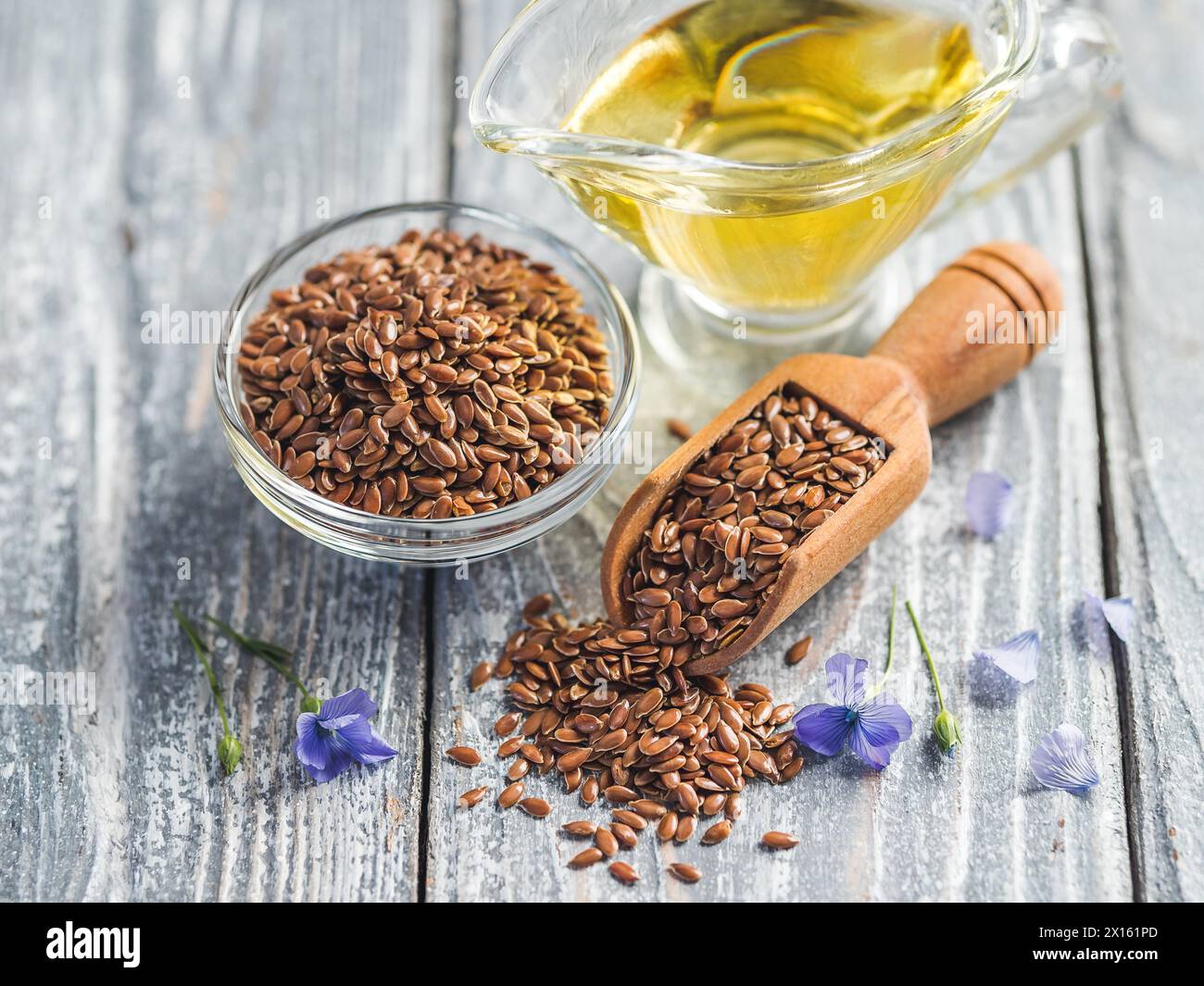 Semi di lino e olio di lino. Semi di lino e olio di lino marroni su sfondo di legno grigio antico. Copia spazio Foto Stock