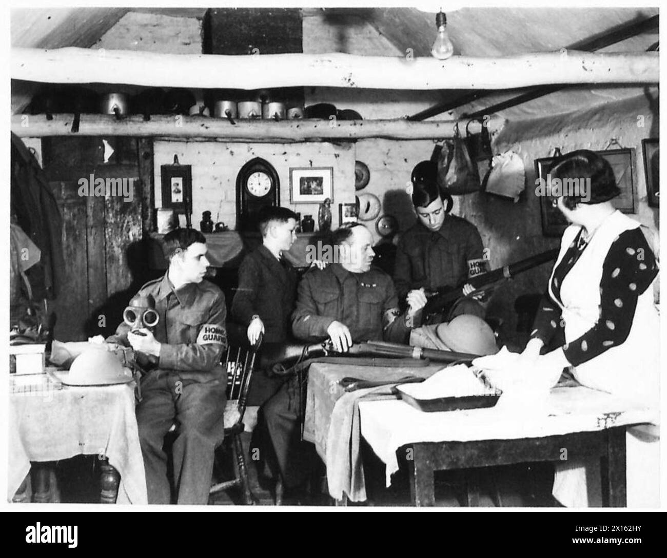 GUARDIA DOMESTICA IN ADDESTRAMENTO - il sergente maggiore V. Hollness e i suoi due figli, membri della Guardia interna, si preparano a partecipare alla sfilata, mentre la signora Hollness prepara la cena domenicale dell'esercito britannico Foto Stock