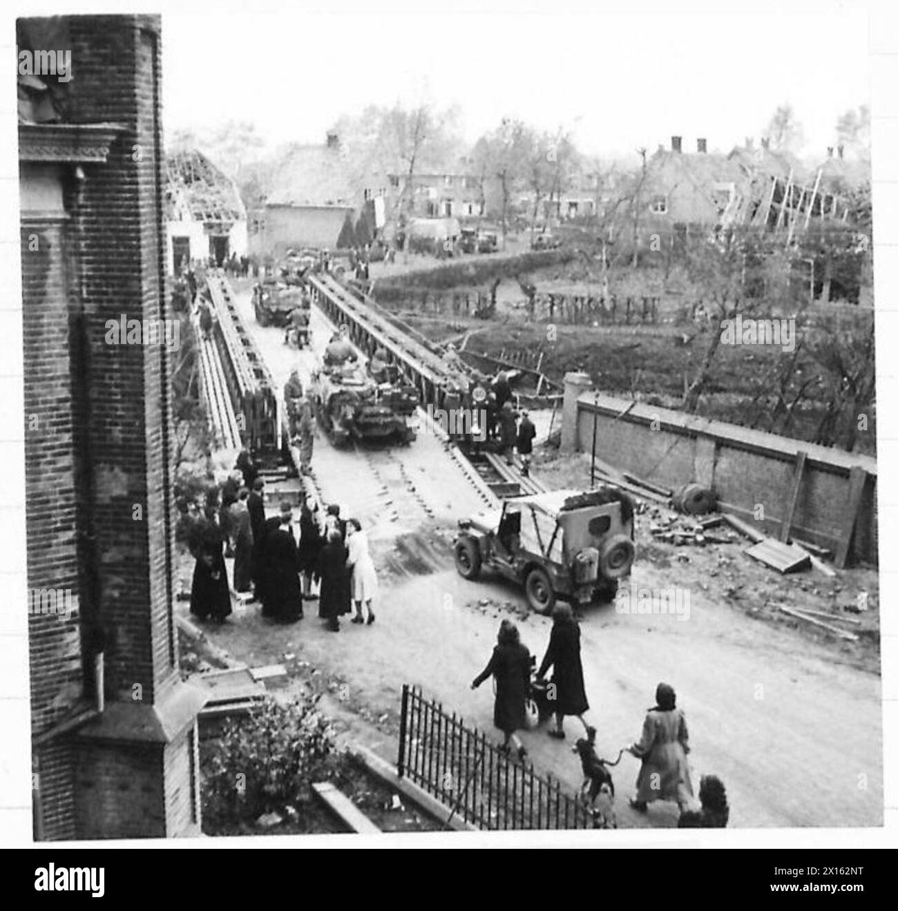 Carri armati e portaerei dell'esercito britannico attraversano un ponte per intercettare il trasporto nemico, con i rifugiati visibili in alcune località durante le operazioni della seconda guerra mondiale. Foto Stock