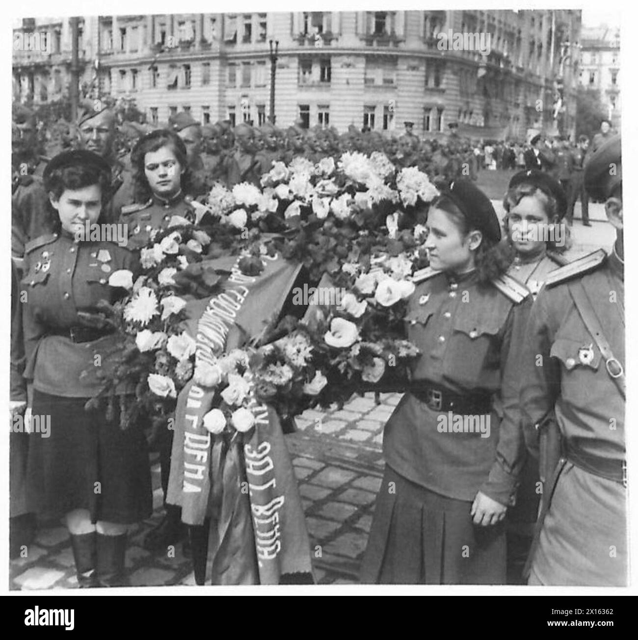 Le donne russe portano una corona al Russian Memorial durante una cerimonia di inaugurazione a Vienna, osservata dal personale dell'esercito britannico. Foto Stock