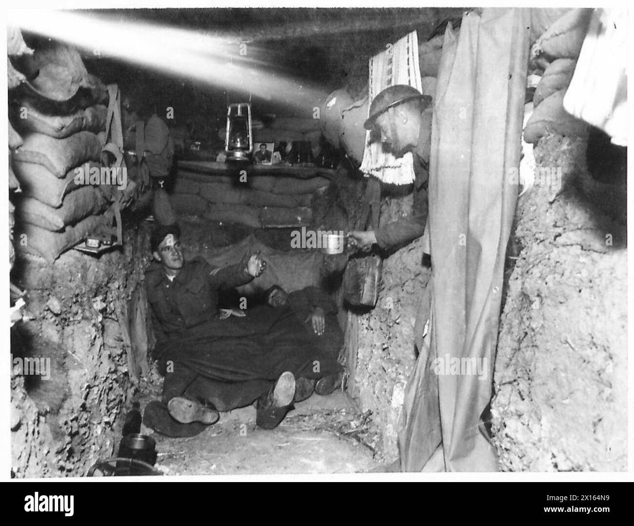 I soldati sono all'interno di un'area scavata che si prepara alle operazioni, gestisce le attrezzature e riposa tra le attività. Foto Stock